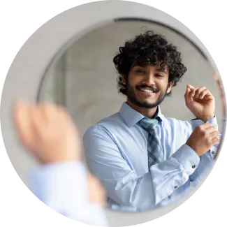 A man in a shirt and tie gazes into a mirror, reflecting on self-improvement and positive societal change